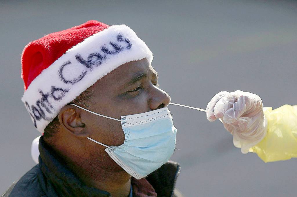 Tim Tai/The Philadelphia Inquirer/TNS 
Anthony Harvin wears a Santa hat as he receives a coronavirus test from Dante Terracciano of Philly Fighting COVID at Vine Memorial Baptist Church in West Philadelphia on Saturday. Staff from Philly Fighting COVID and the Childrens Hospital of Philadelphia offered free testing organized by the traveling Community-Accessible Testing & Education (CATE) program, which offers testing at different sites across Pennsylvania.