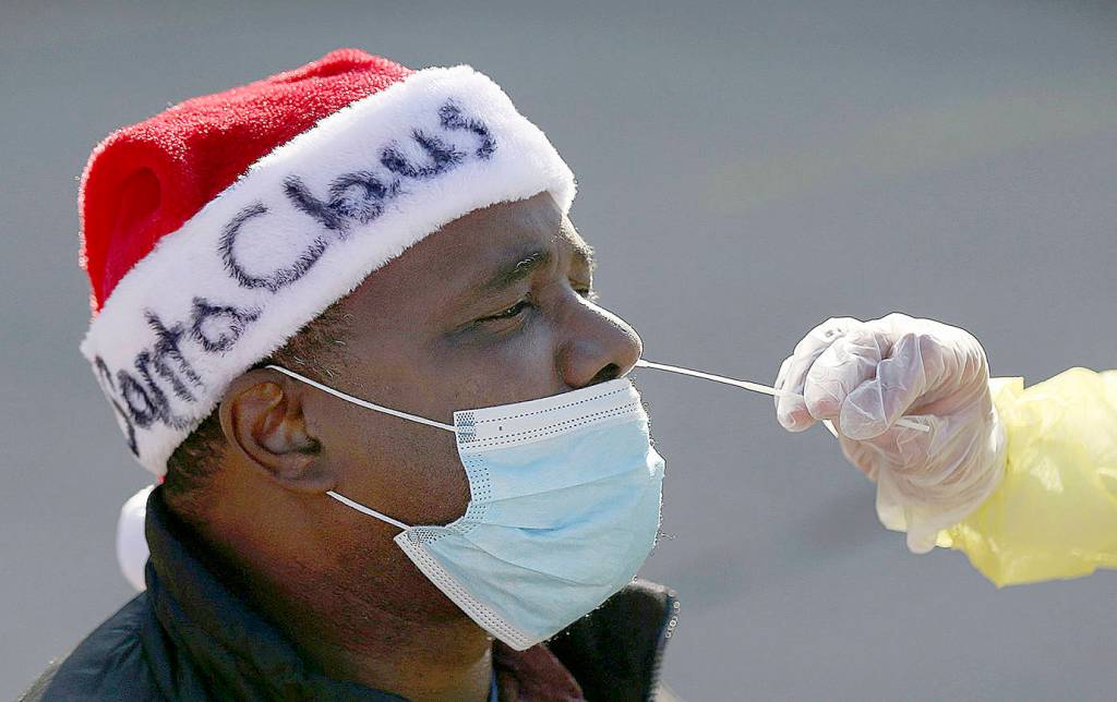 Anthony Harvin wears a Santa hat as he receives a coronavirus test from Dante Terracciano of Philly Fighting COVID at Vine Memorial Baptist Church in West Philadelphia on Saturday. Staff from Philly Fighting COVID and the Children's Hospital of Philadelphia offered free testing organized by the traveling Community-Accessible Testing & Education (CATE) program, which offers testing at different sites across Pennsylvania. (Tim Tai/The Philadelphia Inquirer/TNS)