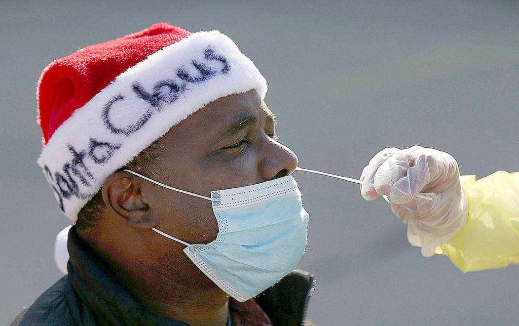 Anthony Harvin wears a Santa hat as he receives a coronavirus test from Dante Terracciano of Philly Fighting COVID at Vine Memorial Baptist Church in West Philadelphia on Saturday. Staff from Philly Fighting COVID and the Children's Hospital of Philadelphia offered free testing organized by the traveling Community-Accessible Testing & Education (CATE) program, which offers testing at different sites across Pennsylvania. (Tim Tai/The Philadelphia Inquirer/TNS)