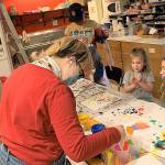 Aberdeen High School senior Delaney Olson (foreground) helps Mae Gambee, 4, choose a new color to add to her artwork on Saturday at the Cosi Art Center. Mae is with her mom, Sarah Gambee, and baby brother Grant. (Kat Bryant | The Daily World)