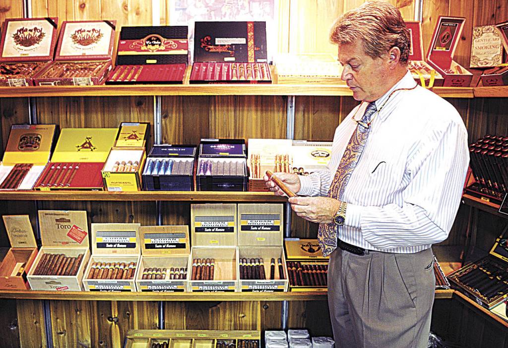 Waughs Mens & Womens Apparels former owner Ray Ericks holds a Monte Cristo cigar in one of the specialty rooms in his store in downtown Aberdeen. (Daily World file photo)