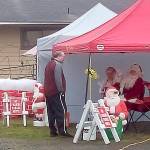 Elks Lodge photographer Thomas Roff discusses photo strategy with Santa and Mrs. Claus prior to the cars rolling through last Saturday in Hoquiam.
