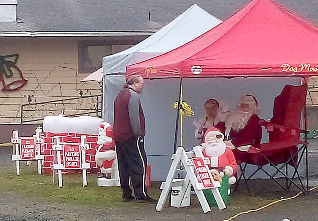 Elks Lodge photographer Thomas Roff discusses photo strategy with Santa and Mrs. Claus prior to the cars rolling through last Saturday in Hoquiam.