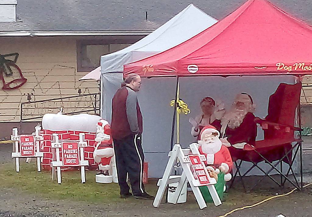 Elks Lodge photographer Thomas Roff discusses photo strategy with Santa and Mrs. Claus prior to the cars rolling through last Saturday in Hoquiam.