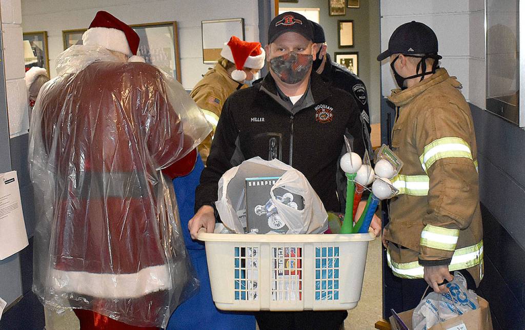 DAN HAMMOCK | THE DAILY WORLD 
Hoquiam Assistant Fire Chief Matt Miller takes a basket of gifts to the police departments mobile command post vehicle Monday.