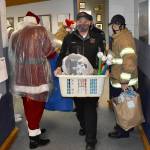 DAN HAMMOCK | THE DAILY WORLD 
Hoquiam Assistant Fire Chief Matt Miller takes a basket of gifts to the police departments mobile command post vehicle Monday.
