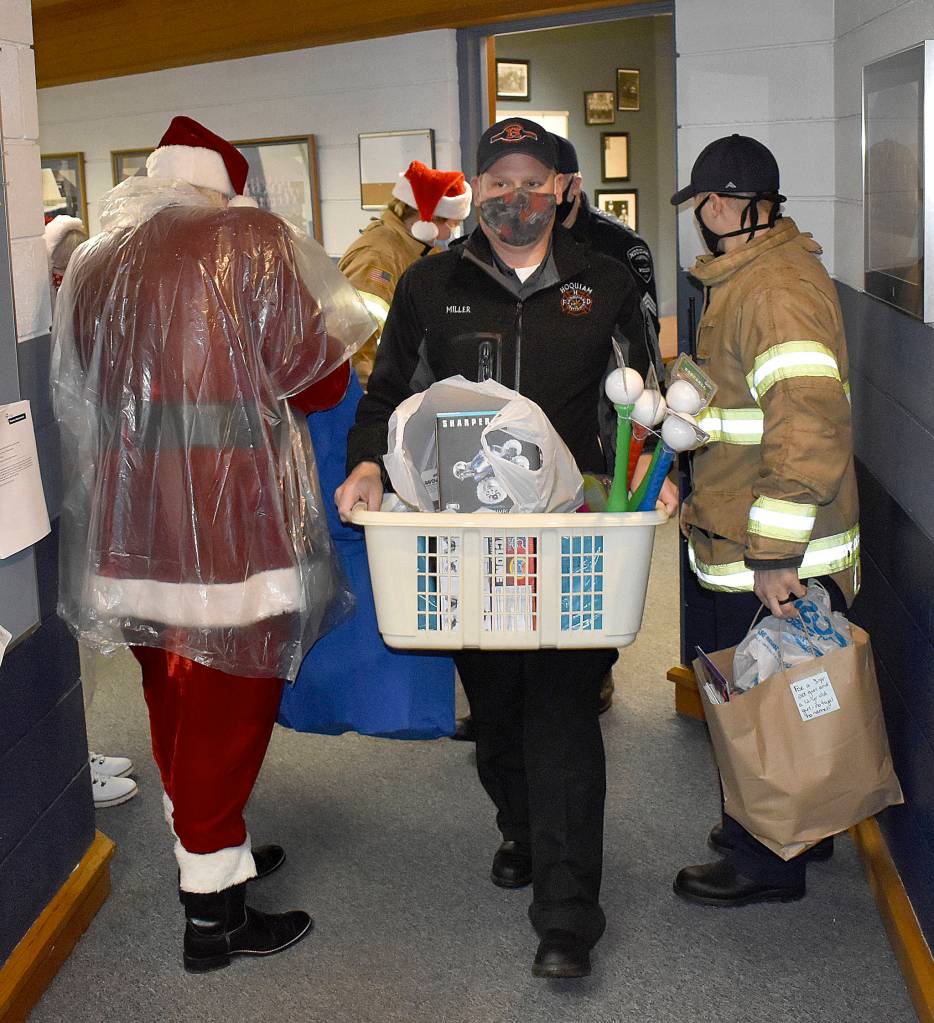 DAN HAMMOCK | THE DAILY WORLD 
Hoquiam Assistant Fire Chief Matt Miller takes a basket of gifts to the police departments mobile command post vehicle Monday.