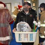 DAN HAMMOCK | THE DAILY WORLD 
Hoquiam Assistant Fire Chief Matt Miller takes a basket of gifts to the police departments mobile command post vehicle Monday.