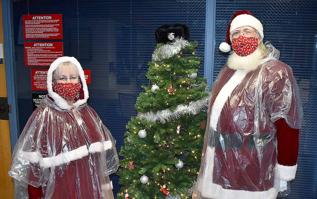 DAN HAMMOCK | THE DAILY WORLD 
Santa and Mrs. Claus  BJ and Neal Fisher  stand beside the Hoquiam Police Department giving tree before heading out to deliver toys to families throughout the town. Below, Mrs. Claus and elves from the Hoquiam police and fire departments delivered gifts to this family on Chenault Avenue on Monday.