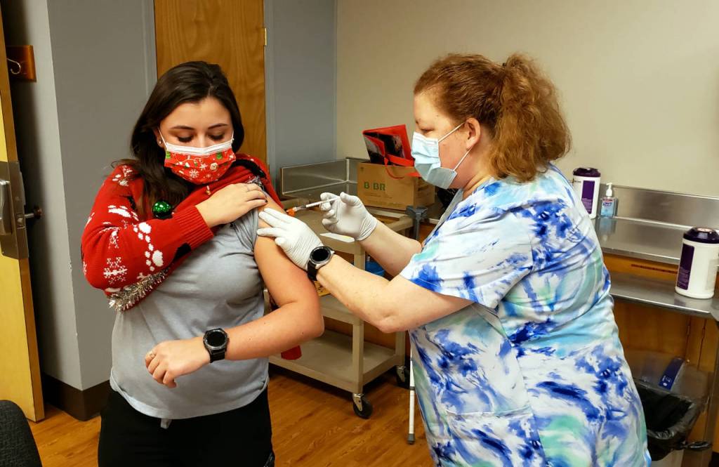 Grays Harbor Community Hospital stenographer Madison Studer, left, received a COVID-19 vaccination from nurse Jeannie Roth during the first day of vaccinations on Tuesday in Aberdeen. (Ryan Sparks | the Daily World)