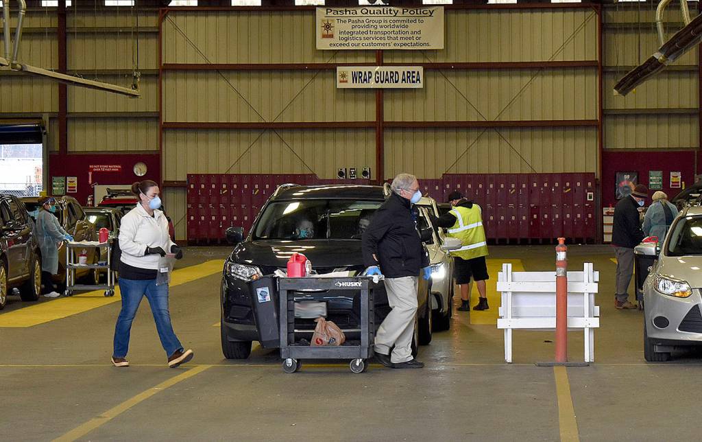 DAN HAMMOCK | THE DAILY WORLD 
Carts were wheeled between the rows of vehicles at the covered mass vaccination site and doses were quickly administered in the last group Friday, when 317 people were scheduled to be vaccinated.