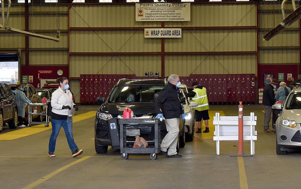 DAN HAMMOCK | THE DAILY WORLD 
Carts were wheeled between the rows of vehicles at the covered mass vaccination site and doses were quickly administered in the last group Friday, when 317 people were scheduled to be vaccinated.