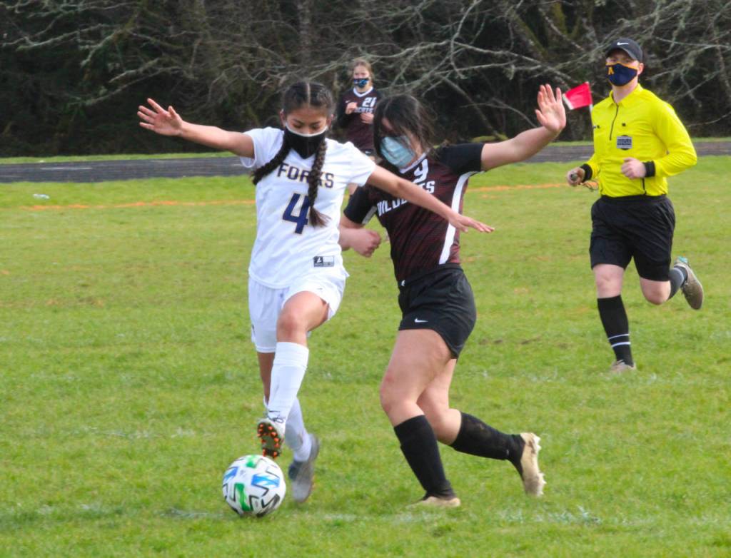 Ocosta sophomore Natalie Carloza (9) attempts to gain possession from Forks midfielder Leslie Hernandez-Beltran during the Wildcats 8-0 win on Saturday in Westport. (Photo by Ben Winkelman)
