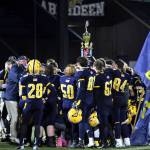 PHOTO BY BEN WINKELMAN Aberdeen head coach Todd Bridge, left, speaks with his team as the Bobcats raise the Myrtle Street Trophy after defeating Hoquiam 30-8 in the 115th Myrtle Street Rivalry game on Saturday in Aberdeen.