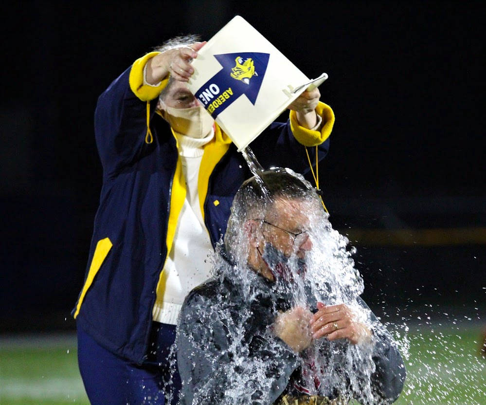 PHOTO BY BEN WINKELMAN Hoquiam School District Superintendent Mike Villarreal (sitting) makes good on a friendly wager with Aberdeen SD Superintendent Dr. Alicia Henderson after Aberdeens 30-8 win on Saturday at Stewart Field in Aberdeen.