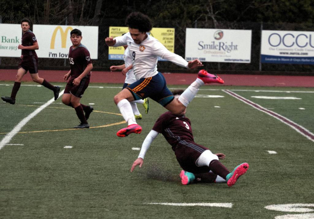 Montesanos Tucker Stecher (3) performs a successful slide tackle against Forks Tony Flores-Hernandez during the Bulldogs 3-0 season-opening loss on Wednesday in Montesano. (Ryan Sparks | The Daily World)