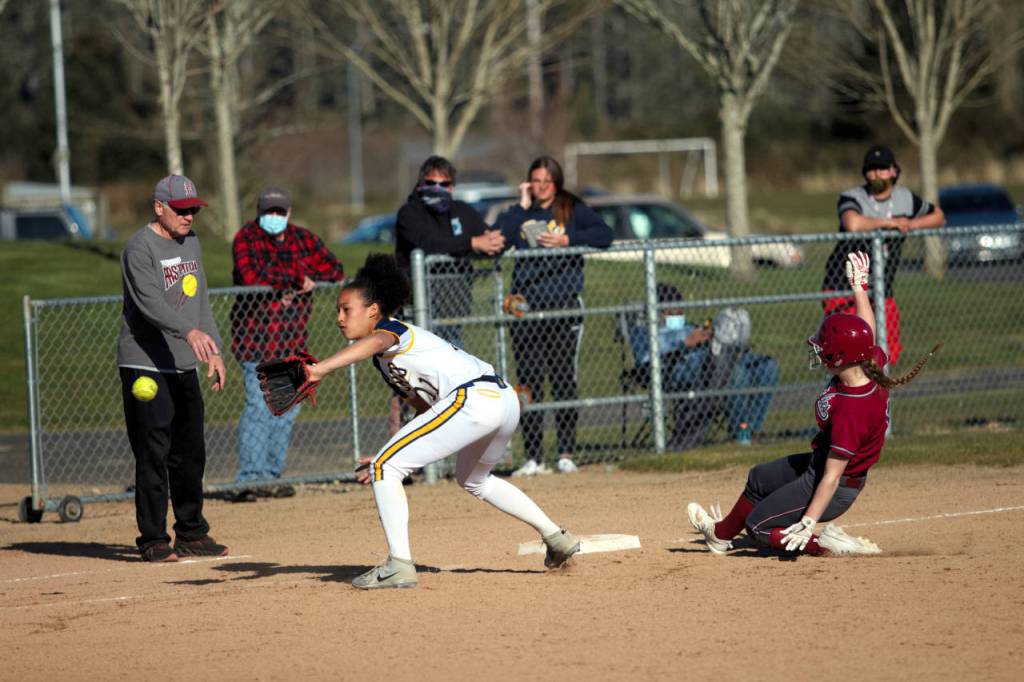 Hoquiams Ella Folkers slides in safe at third base against Aberdeen fielder Madisyn Gore during Aberdeens 15-11 victory on Monday. Below, Aberdeen infielder Logan Glanz records an out during the Bobcats victory.
