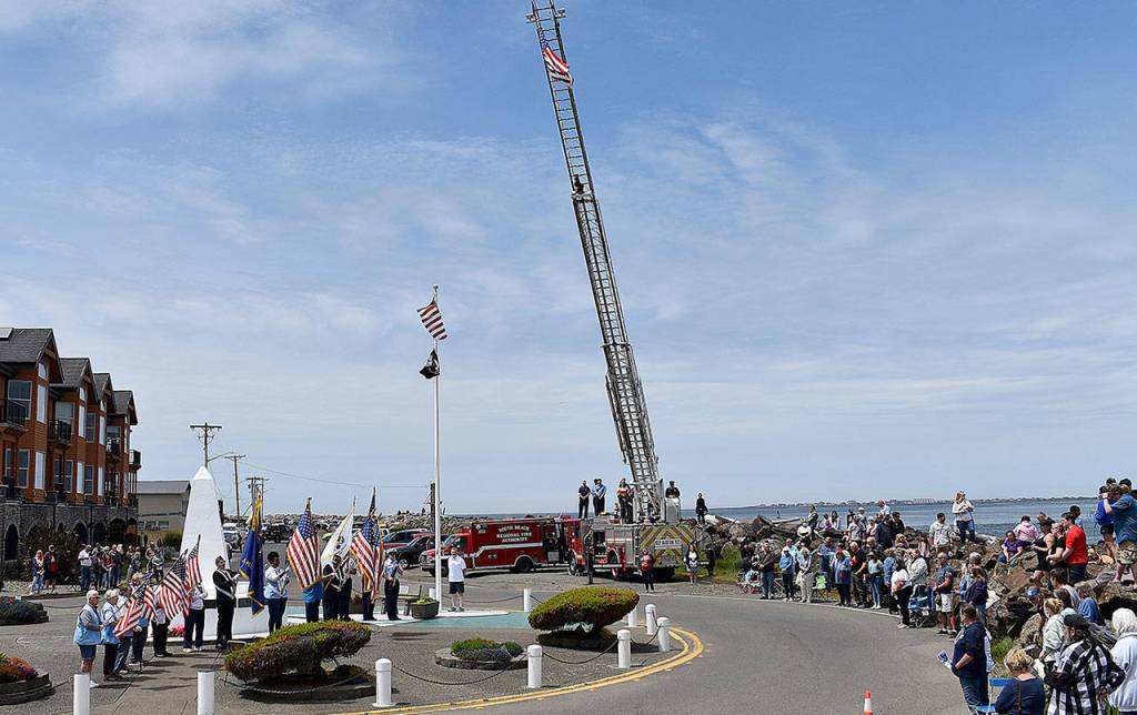 DAN HAMMOCK | THE DAILY WORLD
The presentation of the colors at Sundays Blessing of the Fleet in Westport. Presenting the colors were the U.S. Coast Guard and members of local veterans associations. At center, at the base of the flag pole, Greg Barnes prepares to ring the memorial bell as names of those who lost their lives at sea are read aloud. The ceremony began with the raising of the flag on the South Beach Regional Fire Authority ladder truck in the background.