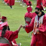 DAN HAMMOCK | THE DAILY WORLD 
Students exchange a fist bump as one waits for her name to be called and the other returns to his seat with his diploma.