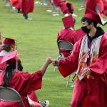 DAN HAMMOCK | THE DAILY WORLD 
Students exchange a fist bump as one waits for her name to be called and the other returns to his seat with his diploma.