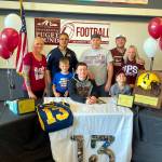 SUBMITTED PHOTO Aberdeen senior Connar Sherman, sitting, is surrounded by family members after signing a National Letter of Intent on Wednesday to play football for the University of Puget Sound in the fall. Pictured are (from left) step-mother Racquel Sherman, Aberdeen assistant coach John Bowers, brother Camden Mayr (blue shirt), father Henry Sherman, step father Josh Mayr, mother Sarah Mayr and sister Shyla Mayr.