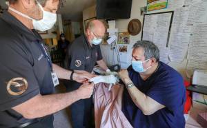 South County Fire paramedic Larry Hadland, left, hands a proof of vaccination card while emergency medical technician Kim Sharpe vaccinates Abel Cordova, 63, at his home on April 20, 2021. Cordova was unable to travel for a vaccination. Greg Gilbert |The Seattle Times