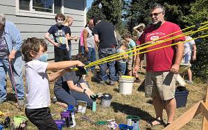 Photo by Kathryn Smith 
Tony Enzler looks on as his son, Winston, prepares to launch a paint-filled balloon at the Cosi Art Center on Saturday, Aug. 28, 2021.