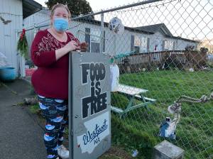 Matthew N. Wells | The Daily World 
Connie Airey, from Westport, holds up the sign that lets her neighbors know that if theyd like food to help them make ends meet, or to spend their money on something else they need, its available.