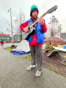 Matthew N. Wells | The Daily World 
Andrew Drew Carey plays his Epiphone acoustic guitar, with four working strings, on Friday Jan. 7, 2022, at the now non-sanctioned homeless encampment behind Aberdeen City Hall. The camp was closed after a narrow city council vote in November 2021.