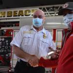 Matthew N. Wells | The Daily World 
Dennis Benn, fire chief at South Beach Regional Fire Authority, left, shakes hands with Dan Wirth, executive director of American Red Cross South Puget Sound and Olympics Chapter, after Wirth helped present Benn and his crew an award on Friday, Feb. 11, 2022, for saving the life of a family in Grayland through a joint campaign to ensure homes have working smoke alarms.