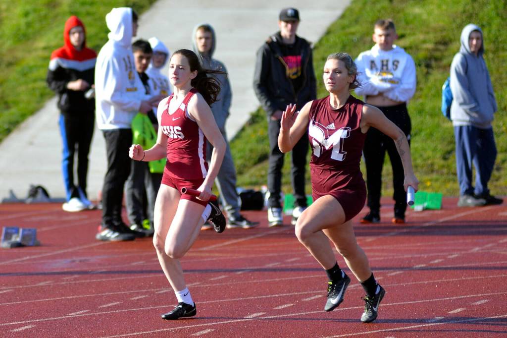 RYAN SPARKS | THE DAILY WORLD Hoquiams Katlyn Brodhead, left, and Montesanos Sierra Birdsall race around the turn during the girls 4x200-meter race during the Ray Ryan Memorial Grays Harbor Championships on Friday in Montesano.