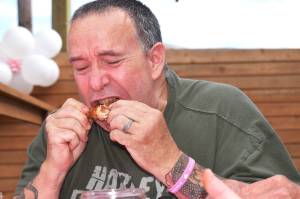 Matthew N. Wells | The Daily World 
Bernie Houle winces as he tears through one of the six chicken wings he finished during the Beat the Heat Challenge. The wing eating contest was to support the finding of Oakley Carlson. It was held on Saturday, Aug. 27, 2022, at Mount Olympus Brewing.