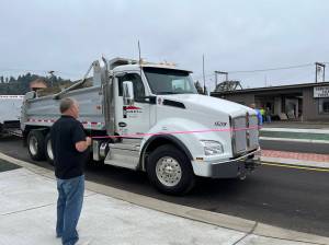 Matthew N. Wells | The Daily World
Aberdeen Mayor Pete Schave drives a Rognlins Inc. dump truck through the new roundabout just after noon on Wednesday, Sept. 14, 2022. Rick Sangder, public works director for the city of Aberdeen, left, held the left end of the pink ribbon. City Engineer Nick Bird held the right end of the ribbon. The roundabout replaces the former five-way intersection of East Market Street, F Street and the one-way street, Fuller Way.