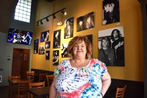 Amy Mathews Smith poses for a photo in front of a wall full of Darrell Westmoreland photos of musicians from her era, inside Nirvana Coffee Co. Mathews Smith opened Nirvana Coffee Co.  205 S. I St., in Aberdeen  Thursday, Oct. 6. While she figures out the customer flow for the business, her hours will be 7 a.m. to 3 p.m. According to the business Facebook page, the coffee shop will be open seven days per week. (Matthew N. Wells | The Daily World)