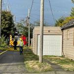 A firefighter walks down the alley behind a residential structure fire in Hoquiam on Thursday. (Michael S. Lockett / The Daily World)