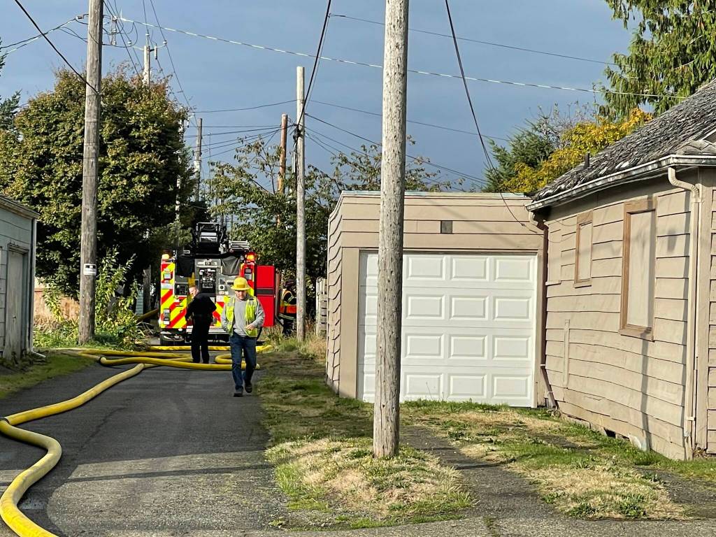 A firefighter walks down the alley behind a residential structure fire in Hoquiam on Thursday. (Michael S. Lockett / The Daily World)