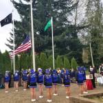 Members of the Elma High School Dance Drill team stand and salute as a new flag is hoisted to half-staff to celebrate Veterans Day during the memorial ceremony at the Elma Veterans Memorial Park.