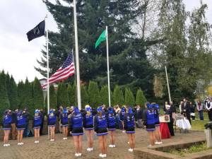 Members of the Elma High School Dance Drill team stand and salute as a new flag is hoisted to half-staff to celebrate Veterans Day during the memorial ceremony at the Elma Veterans Memorial Park.