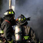 A firefighter points something out to their colleague as they attack a structure fire in Elma on Nov. 15. (Michael S. Lockett / The Daily World)