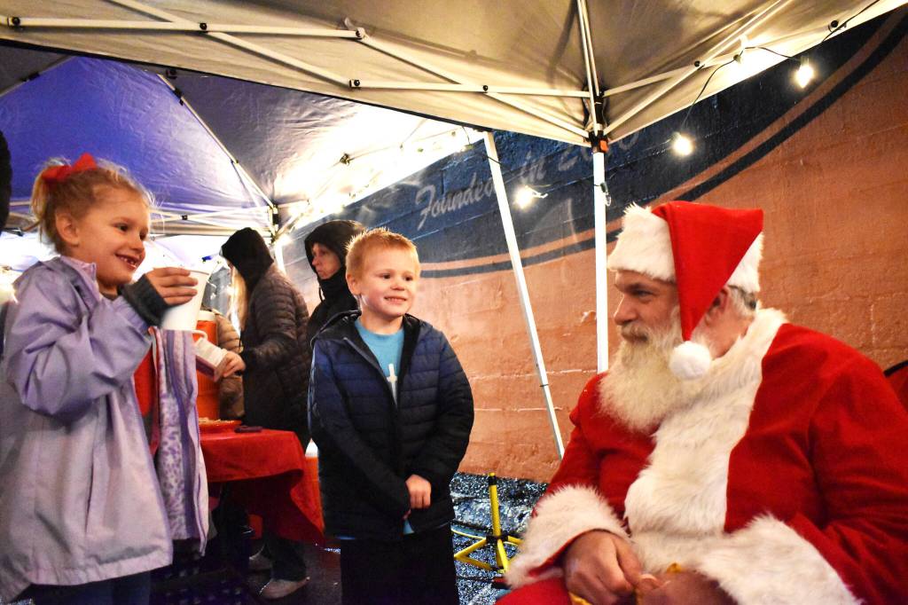Clayton Franke / The Daily World 
Emmie Niemann, left, and Trey McDougal, both 6, chat with Santa Friday evening about what they want for Christmas this year.