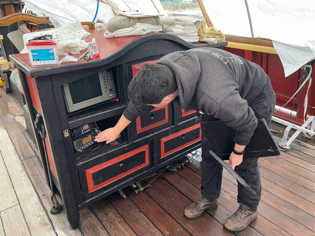 Captain Katherine Pogue of the Lady Washington gestures at the vessels VHF equipment, in line for replacement, on Dec. 6. (Michael S. Lockett / The Daily World)