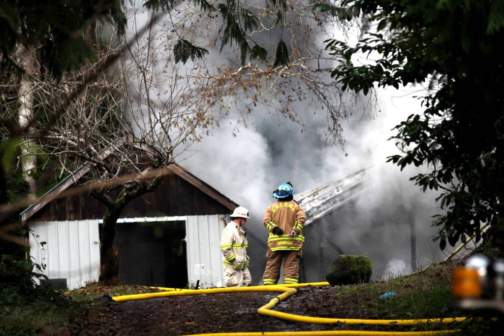 A Grays Harbor Fire District 2 firefighter observes operations combatting a structure fire on Dec. 13. (Michael S. Lockett / The Daily World)
