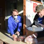 Volunteer Greg Johnstone, left, slides a box of food to Jerry Nelson Dec. 15 at the Aberdeen Salvation Army food pantry, 120 W Wishkah St. The pantry serves roughly triple the amount of people it did one year ago. (Clayton Franke / The Daily World)