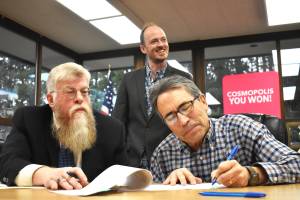 Steve Johnson, attorney for the city of Cosmopolis, watches as Darryl Druzianich, right, signs legal documents that finalize a land donation from the Druzianich family to the city of Cosmopolis. Mayor Kyle Pauley, in back, said the acreage will be a "great opportunity to expand our park space." Pauley said the land will not be developed for anything but green space, which could include sports courts, fields and other activities where the area youth, and other residents, can run and play. (Matthew N. Wells / The Daily World)