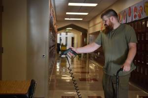 Clayton Franke / The Daily World 
Brandon Hobgood, an evening custodian with the North Beach School District, sprays disinfectant on a desk at Ocean Shores Elementary School Tuesday afternoon.