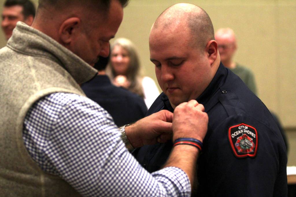 New Firefighter/EMT George Foster is pinned during a swearing-in ceremony for the Ocean Shores Fire Department by his father, Dave Foster on Feb. 13. (Michael S. Lockett / The Daily World)
