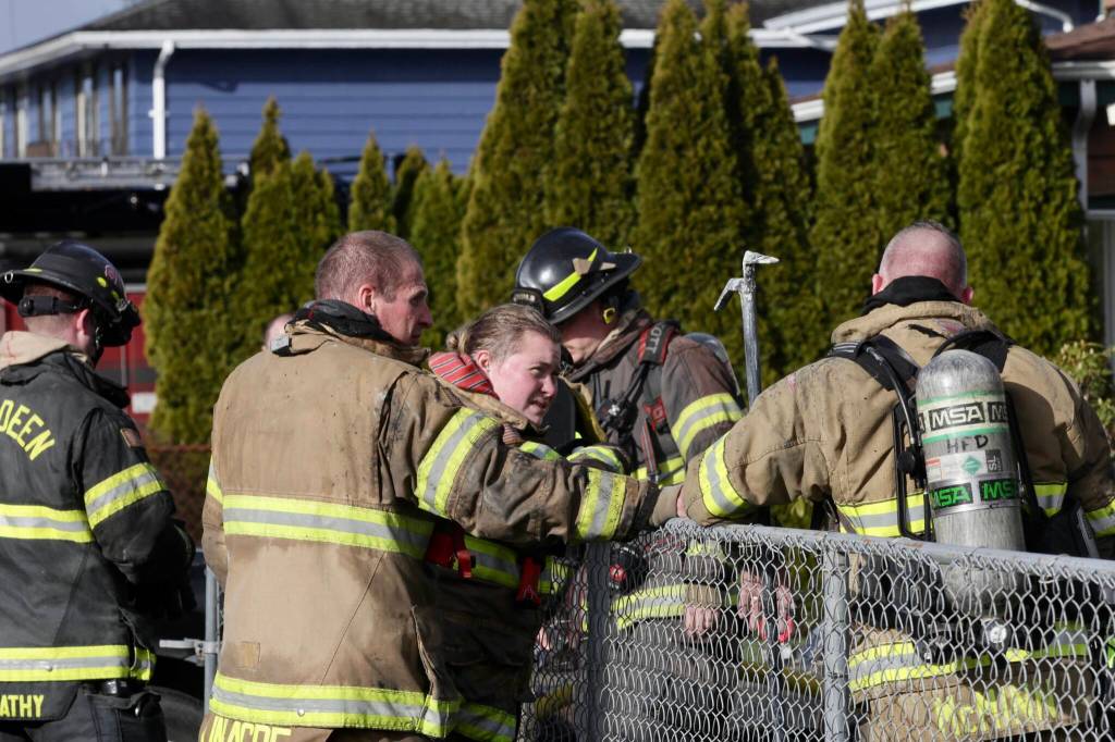 Firefighters converse after fighting a structure fire in a two-story house in Hoquiam to a standstill on Friday morning, Feb. 17. (Michael S. Lockett / The Daily World)