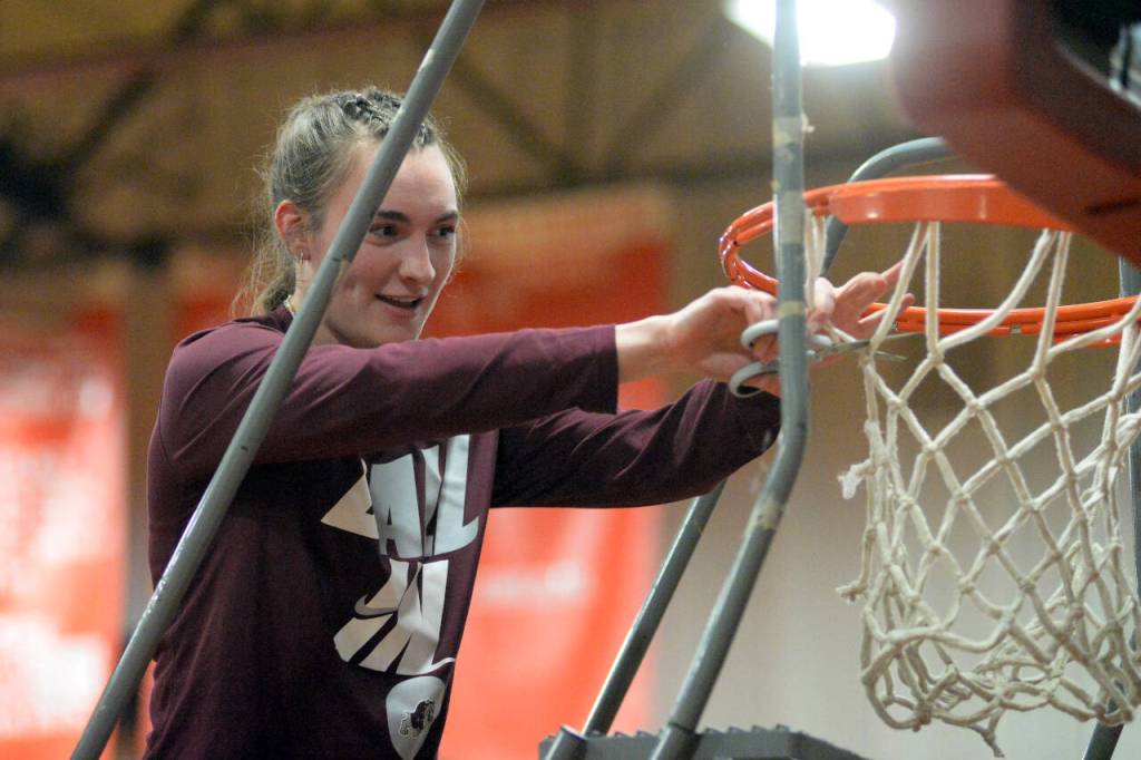 RYAN SPARKS | THE DAILY WORLD Montesano senior center Addie Winter, who has been sidelined this season with a knee injury, cuts down the net after the Bulldogs defeated Seton Catholic 72-36 in the district-championship game on Friday in Castle Rock.