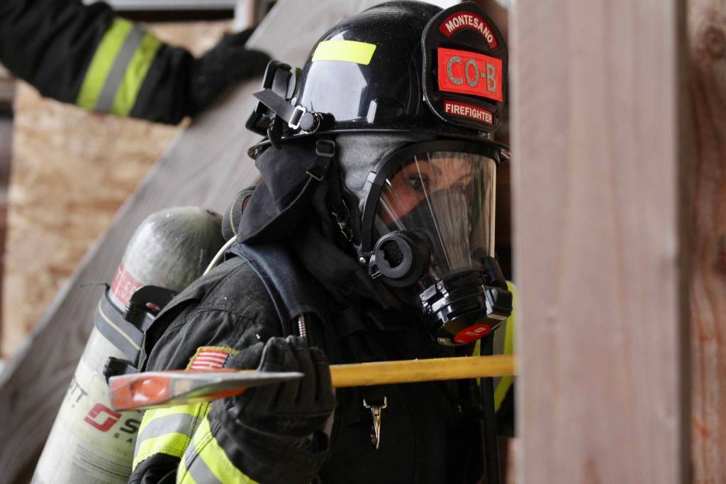 Volunteer firefighter Kori Goudey of the Montesano Fire Department practices breaching through a vertical wall with an axe during a firefighter academy in Westport on Feb. 18.