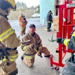 Capt. Keith Zelepuza of the South Beach Regional Fire Authority, kneeling, demonstrates a forcible entry technique during a firefighter academy on Feb. 18 in Westport. (Michael S. Lockett / The Daily World)